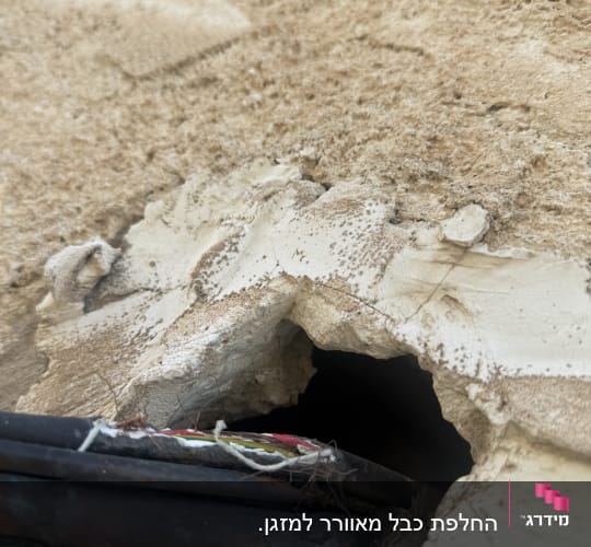 חור בקיר עם כבלים חשמליים חשופים
